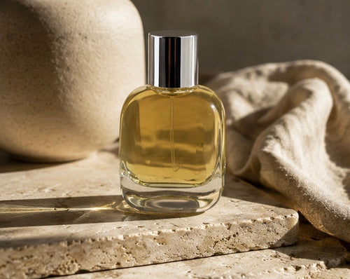 Axiom Grey eau de parfum bottle on warm marble in dappled light